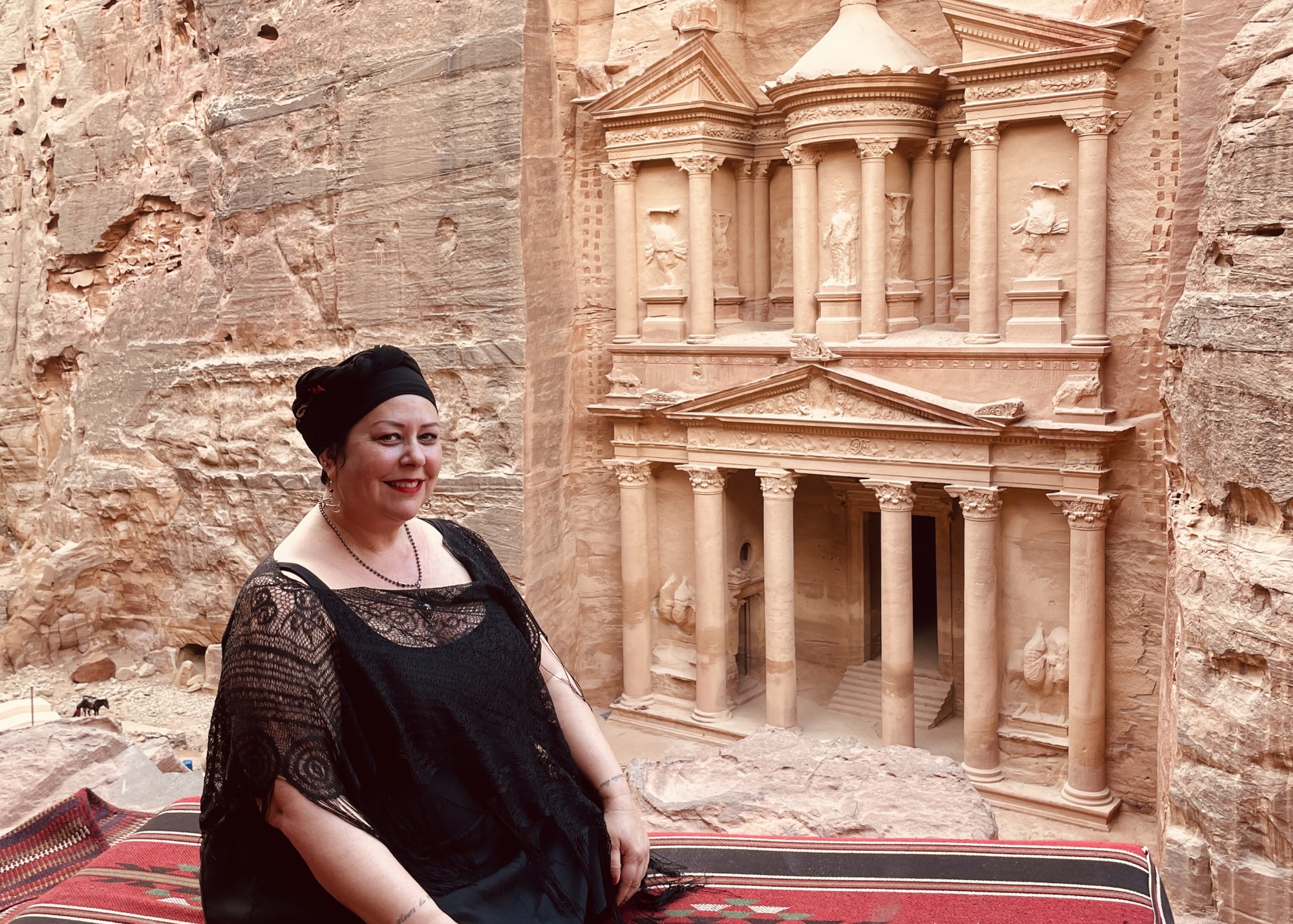 Liisa sitting on a mat and posing at a lookout at Petra